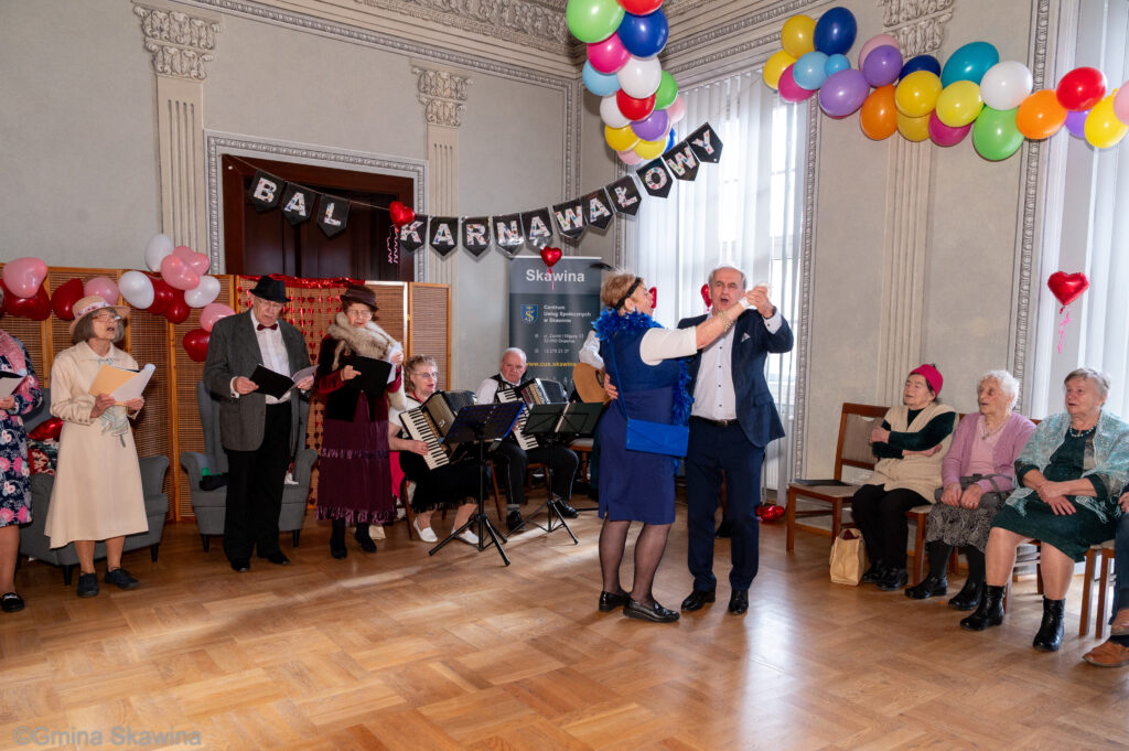 W tle gra kapela na pierwszym planie para seniorów tańczy